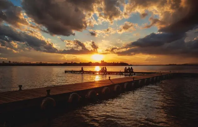 Sol se pondo sobre a água do Lago Paranoá, com a orla escurecendo em silhueta