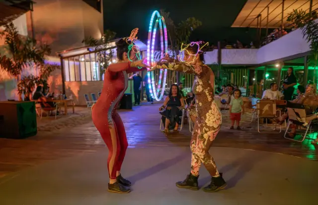 Artista girando aro de fogo diante do público, à noite